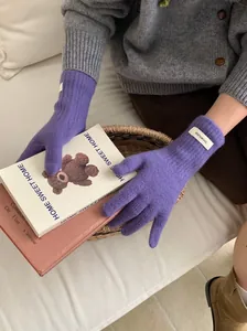 Detailed close-up of purple knitted merino wool gloves featuring a 100% wool label