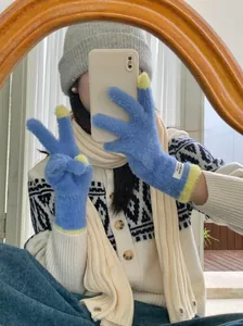 Detailed view of blue coral fleece touchscreen gloves worn in a cozy mirror selfie.