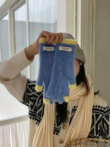 Close-up of soft blue coral fleece gloves with yellow tips and branded cloth tag