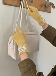 Stylish yellow knitted gloves featuring touch screen design and a minimalist label