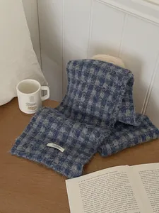 Detailed view of a cozy blue checkered knitted scarf on a wooden table with a book