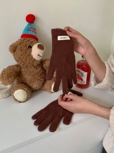 Close-up view of the 100% wool authentication tag on soft brown knitted gloves for women