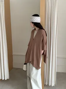 Elegante scialle poncho in maglia marrone indossato da una modella in stile minimal