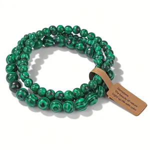 Gros plan d'un ensemble de bracelets élastiques à trois rangs en malachite avec étiquette