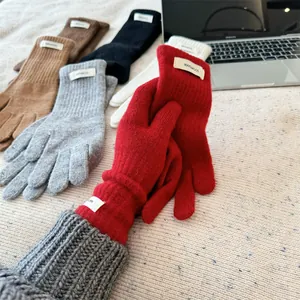 Close-up of multicolored 100% Merino wool gloves on a cozy textured surface