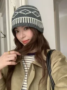 Primo piano di un berretto grigio in maglia Fair Isle con motivo a rombi bianchi.