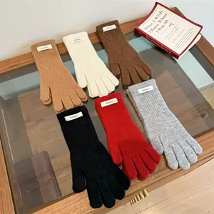 Detailed view of 100% wool merino knitted gloves in multiple colors on a wooden table.