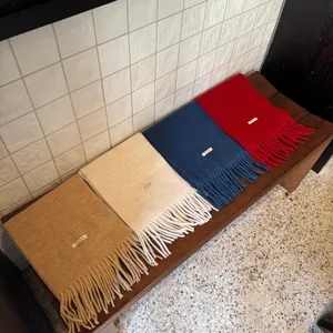 Cuatro colores de bufandas de lana con detalle de flecos en un banco de madera