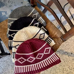 Varietà di berretti in maglia Fair Isle in più colori impilati su una sedia
