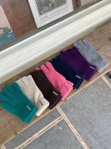 Detailansicht bunter Strickhandschuhe aus Wollmischung mit dekorativen Metallanhängern