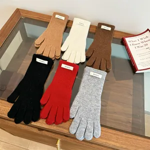 Close-up of 100% wool merino gloves in various solid colors displayed on a glass table