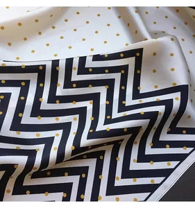 Close-up of silk-like square scarf with elegant chevron and polka dot pattern