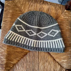 Dettaglio di un berretto in maglia grigio con motivi Fair Isle a rombi bianchi.