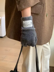 Détail de gants en laine tricotée gris vintage avec un écusson décoratif mouton