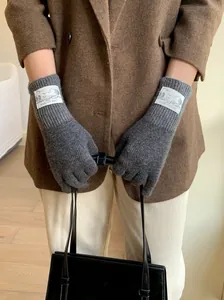 Vue détaillée de gants en laine tricotée grise avec étiquettes de style vintage aux poignets