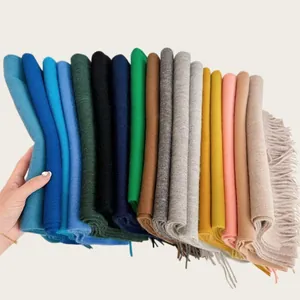 Close-up of a stack of colorful 100% wool scarves showing various solid colors