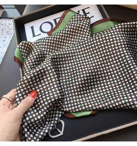 Detail shot of a 70x70cm geometric print silk-like scarf in elegant green and brown tones.