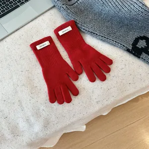 Close-up view of premium red 100% wool knitted winter gloves with a minimalist white tag