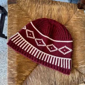 Primo piano del berretto in maglia Fair Isle bordeaux con motivo a rombi bianchi