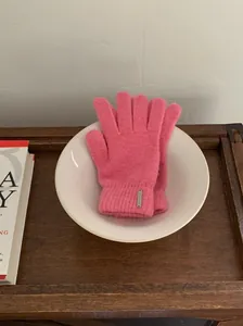 Nahaufnahme von weichen rosa Strickhandschuhen aus Wollmischung in einer weißen Schale