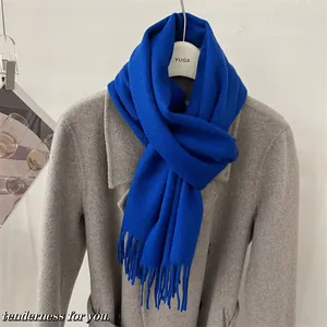 Vue détaillée d'une écharpe en laine australienne bleu roi drapée élégamment sur un manteau gris