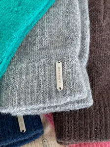 Detaillierte Nahaufnahme von Wollmisch-Winterhandschuhen mit graviertem Metallemblem