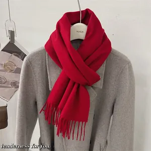 Écharpe rouge en laine 100 % australienne avec pompons sur un manteau d'hiver gris