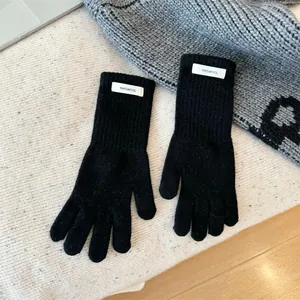 Close-up macro view of black 100% wool knitted gloves showing woven material label