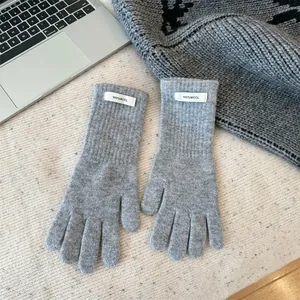 Detail shot of grey 100% merino wool gloves with a small white woven label