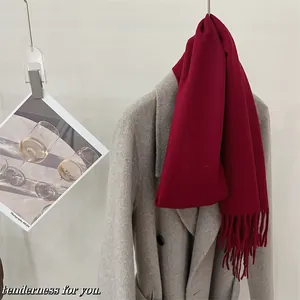 Détail d'une écharpe en pure laine bordeaux avec franges sur un manteau de laine gris