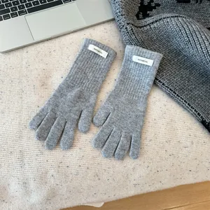 Detail view of grey 100% merino wool knitted winter gloves on a lifestyle desk setup