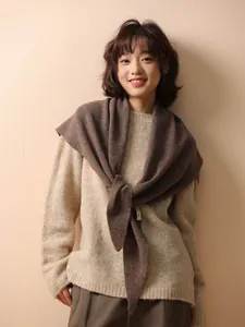 Detailed view of a dark brown 100% wool knitted triangle shawl worn over a sweater