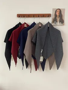 Various colors of 100% Australian wool knitted triangle shawls hanging on a wooden rack