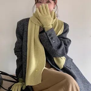Close-up of lime green ribbed knit scarf and matching gloves set worn by a female model