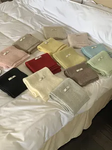 A variety of colorful knitted wool scarves neatly folded and displayed on a bed