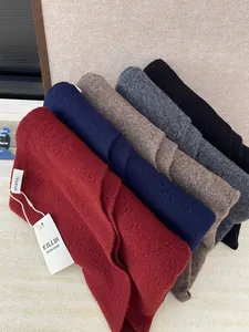 Stack of multi-color 100% Australian wool knitted triangle shawls with hand-made labels.