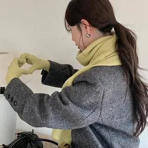 Close-up view of a cozy yellow knitted scarf and matching gloves winter gift set