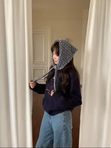 Modelo asiática con una elegante capucha de punto a rayas grises y azules chic