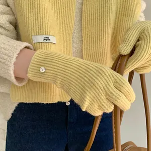 Detailed close-up of soft pastel yellow knitted gloves and matching scarf for winter.