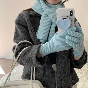 Detail view of light blue knitted scarf and gloves set paired with a stylish grey coat