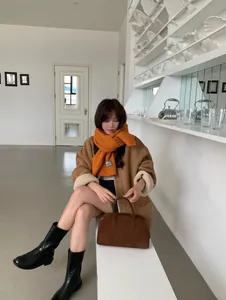 Elegante bufanda de punto naranja jengibre suave usada por una modelo en invierno