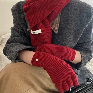Close-up of red chunky knitted scarf and matching gloves set with woven brand tag