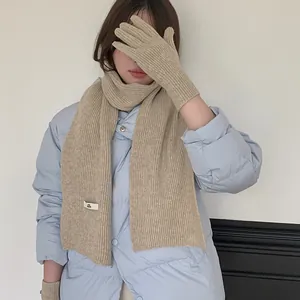 Close-up of beige knitted scarf and gloves set worn with light blue jacket