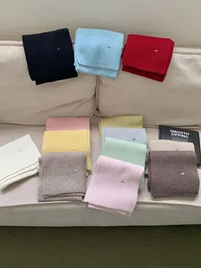 Variety of colorful knit scarves with metal tags displayed on a cozy sofa setting