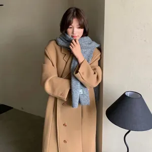 Bufanda de punto gris acogedora y abrigo de lana camel usados por una modelo asiática