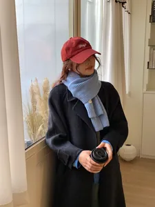 Dettaglio di una morbida sciarpa blu in maglia abbinata a un cappotto invernale