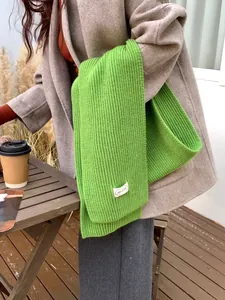 Primo piano di una sciarpa in maglia a coste verde brillante con un elegante cappotto beige.