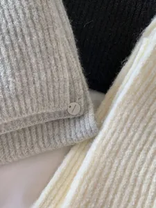 Close-up of soft knitted scarf textures in neutral grey, classic black, and cream white