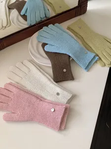 Detailed view of colorful ribbed knit wool gloves with metal tags on a white tabletop