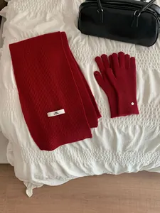 Elegant red knitted scarf and matching gloves set for winter warmth on white bedding